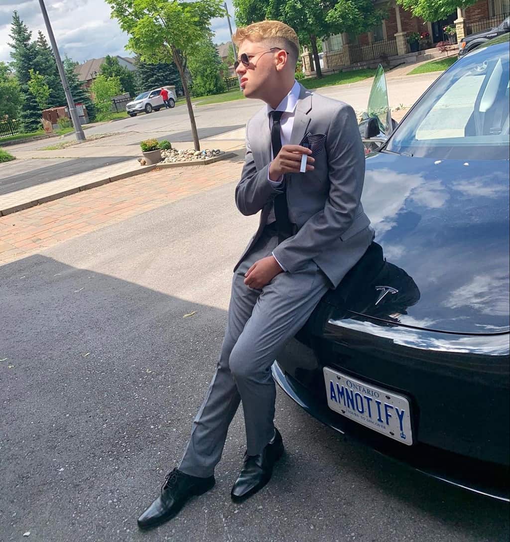 Aaron Maresky in a suit leaning against a car
