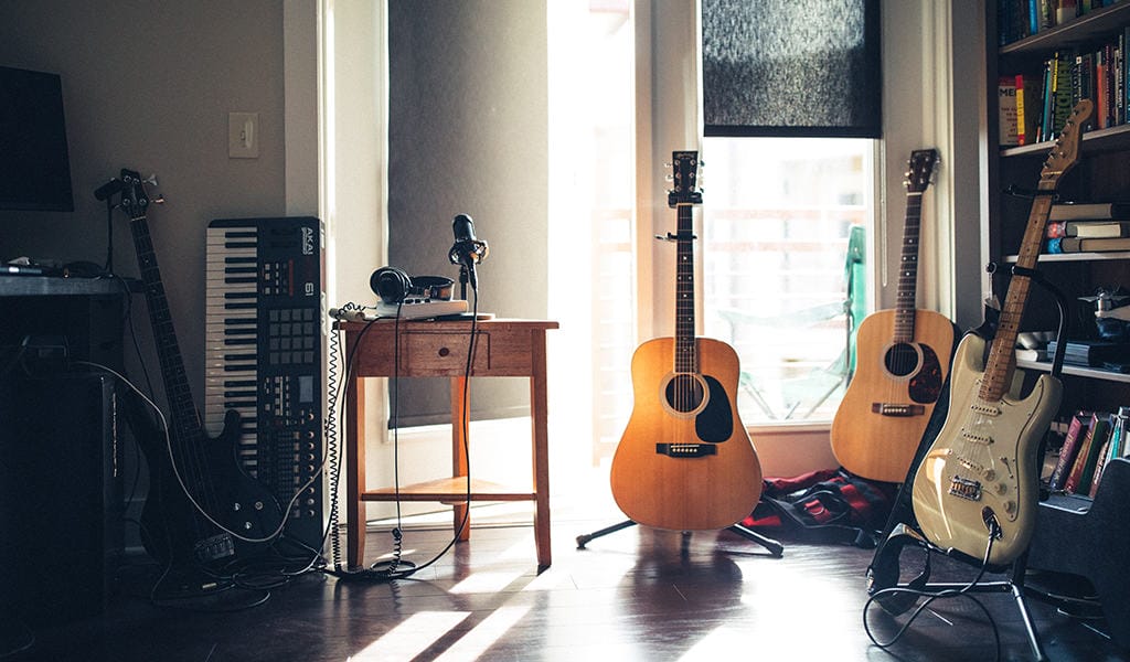 multiple guitars, a keyboard, and a microphone in a home 